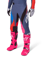 Alpinestars 2025 Techstar Dreem Pants, pantaloni da motocross, grigio scuro con sezioni blu, rosso e rosa, grafiche bianche, indossati con stivali rosa brillante e guanti bianco e nero, design audace ad alta visibilità