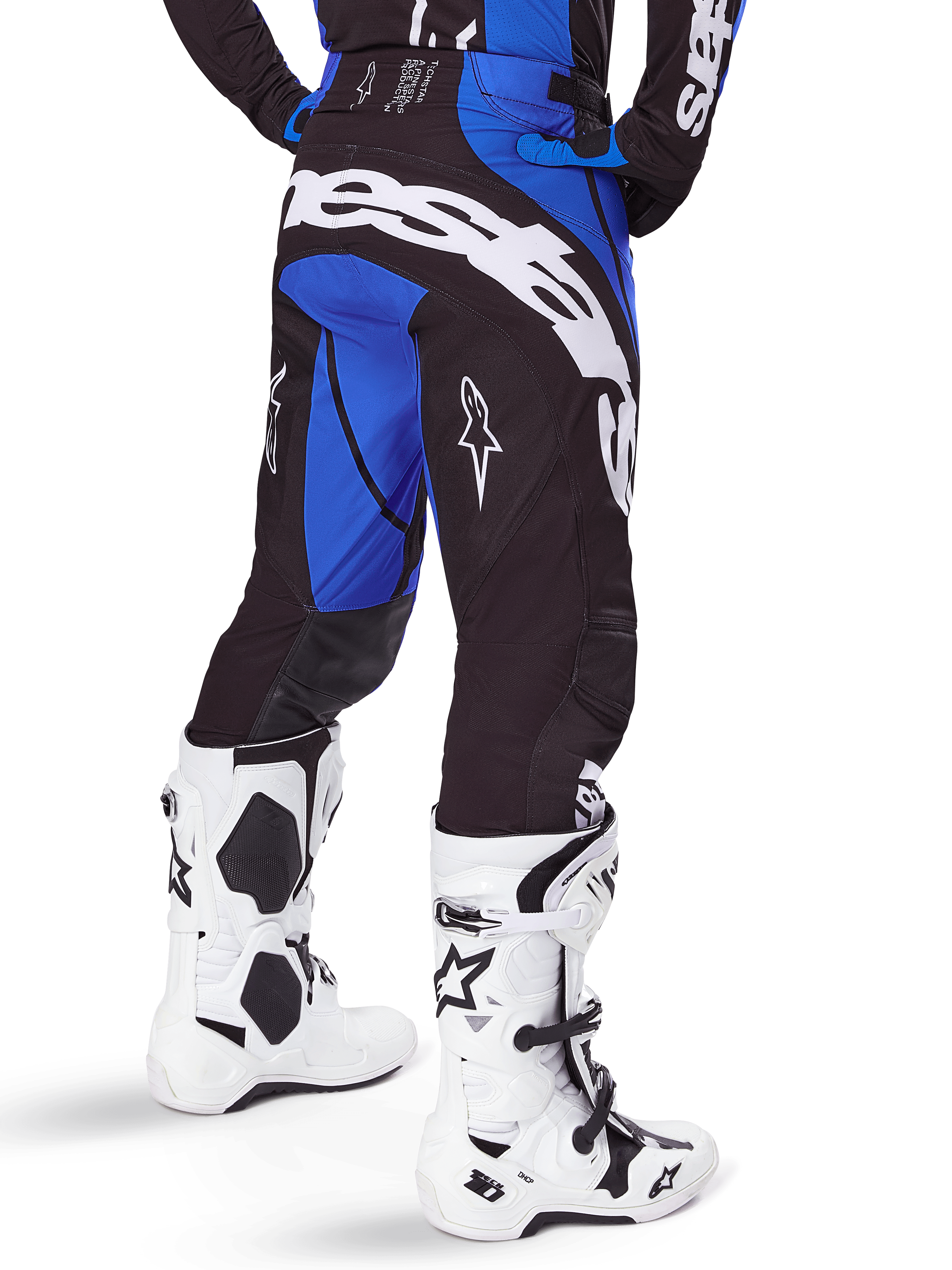 Alpinestars 2025 Techstar Dreem Pants, pantaloni da motocross, nero e blu, vista posteriore con audace marchio Alpinestars bianco sulla seduta, indossati con stivali da motocross bianchi e neri e maglia blu coordinata, vestibilità atletica per gare fuoristrada
