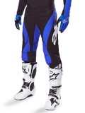 Alpinestars 2025 Techstar Dreem Pants, pantaloni da motocross, nero e blu, indossati con stivali da motocross bianchi e guanti blu, con logo Alpinestars bianco sulla gamba, costruzione resistente per gare fuoristrada