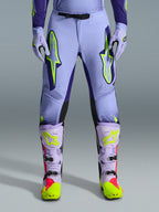 Alpinestars 2026 Supertech Scenz Pants, pantaloni da motocross, viola giallo fluo, con grandi loghi giallo neon sulle cosce, indossati con stivali e guanti da motocross coordinati viola e gialli, design performante con vestibilità atletica per corse fuoristrada