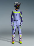Alpinestars 2026 Supertech Scenz Gear Set, completo motocross, viola chiaro e giallo-verde neon, equipaggiamento protettivo completo comprensivo di casco nero con accenti viola, maglia con branding giallo neon, pantaloni coordinati con grafiche a stella e stivali coordinati con dettagli rosa.