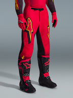 Alpinestars 2026 Supertech Scenz Pants, pantaloni da motocross, rosso, nero e giallo, con loghi Alpinestars gialli e pannelli neri, indossati con maglia rossa coordinata, guanti rossi e stivali da motocross neri