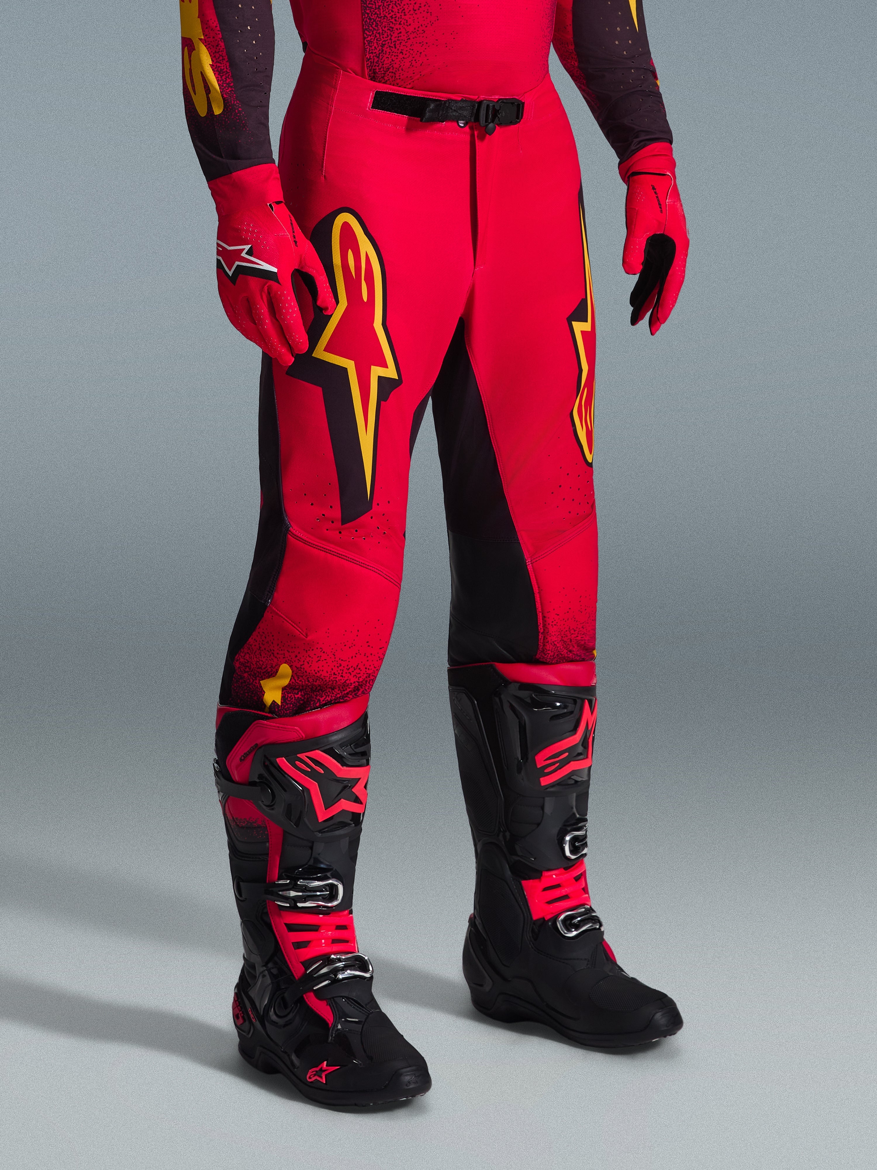 Alpinestars 2026 Supertech Scenz Pants, pantaloni da motocross, rosso, nero e giallo, con loghi Alpinestars gialli e pannelli neri, indossati con maglia rossa coordinata, guanti rossi e stivali da motocross neri