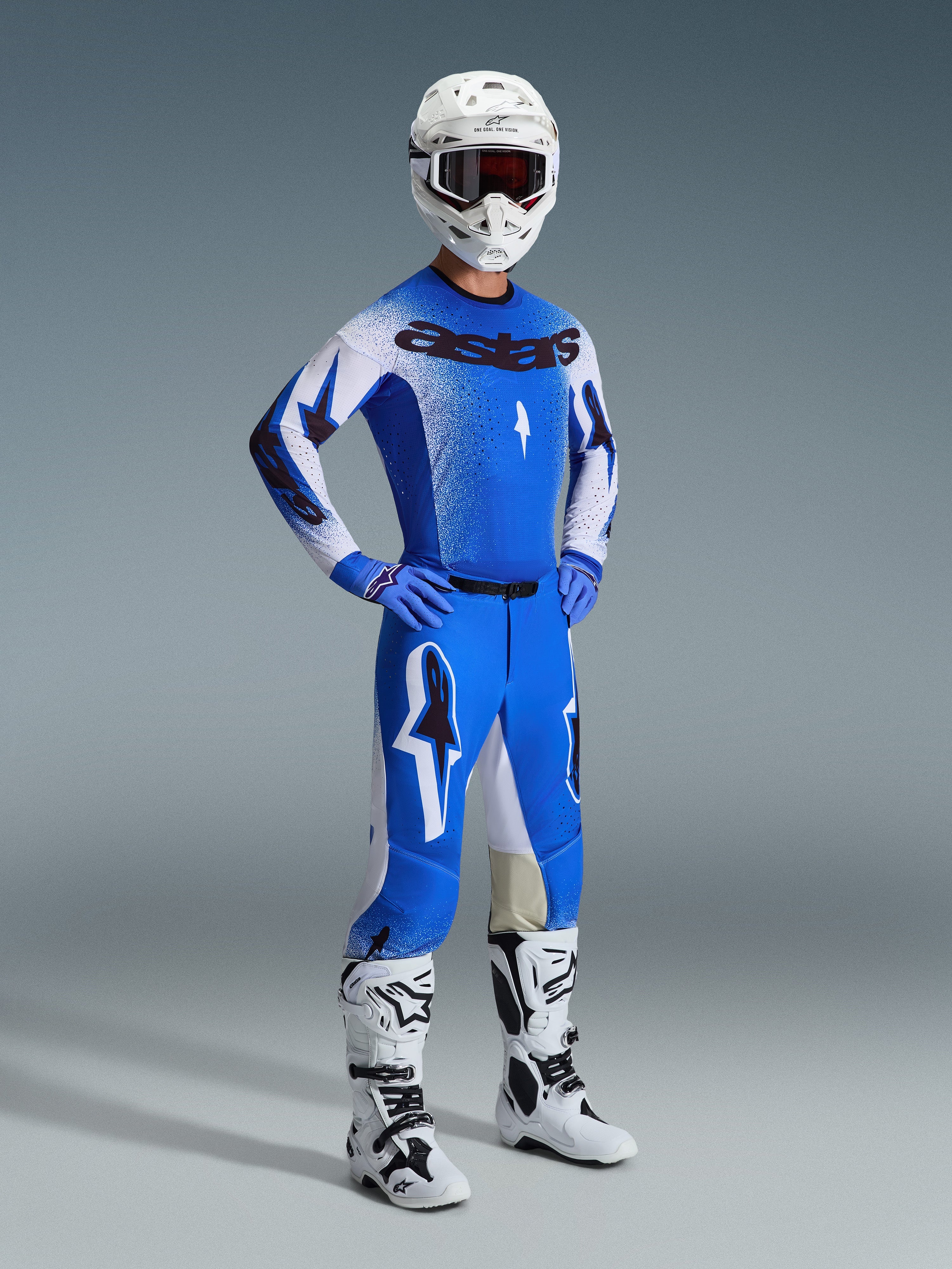 Pilota di motocross con abbigliamento completo da gara, Pantaloni Supertech Scenz 2026 in UCLA Blue e bianco, maglia coordinata blu e bianca con logo Astars, casco bianco con maschera rossa, stivali bianchi e neri, outfit coordinato per competizioni professionistiche fuoristrada.