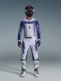 Pilota di motocross con set abbigliamento Alpinestars Supertech Scenz 2026, maglia bianca e blu scuro con pantaloni coordinati, grandi loghi Astars e design grafico puntinato, casco nero, stivali protettivi bianchi e neri, guanti blu, completo da gara professionale
