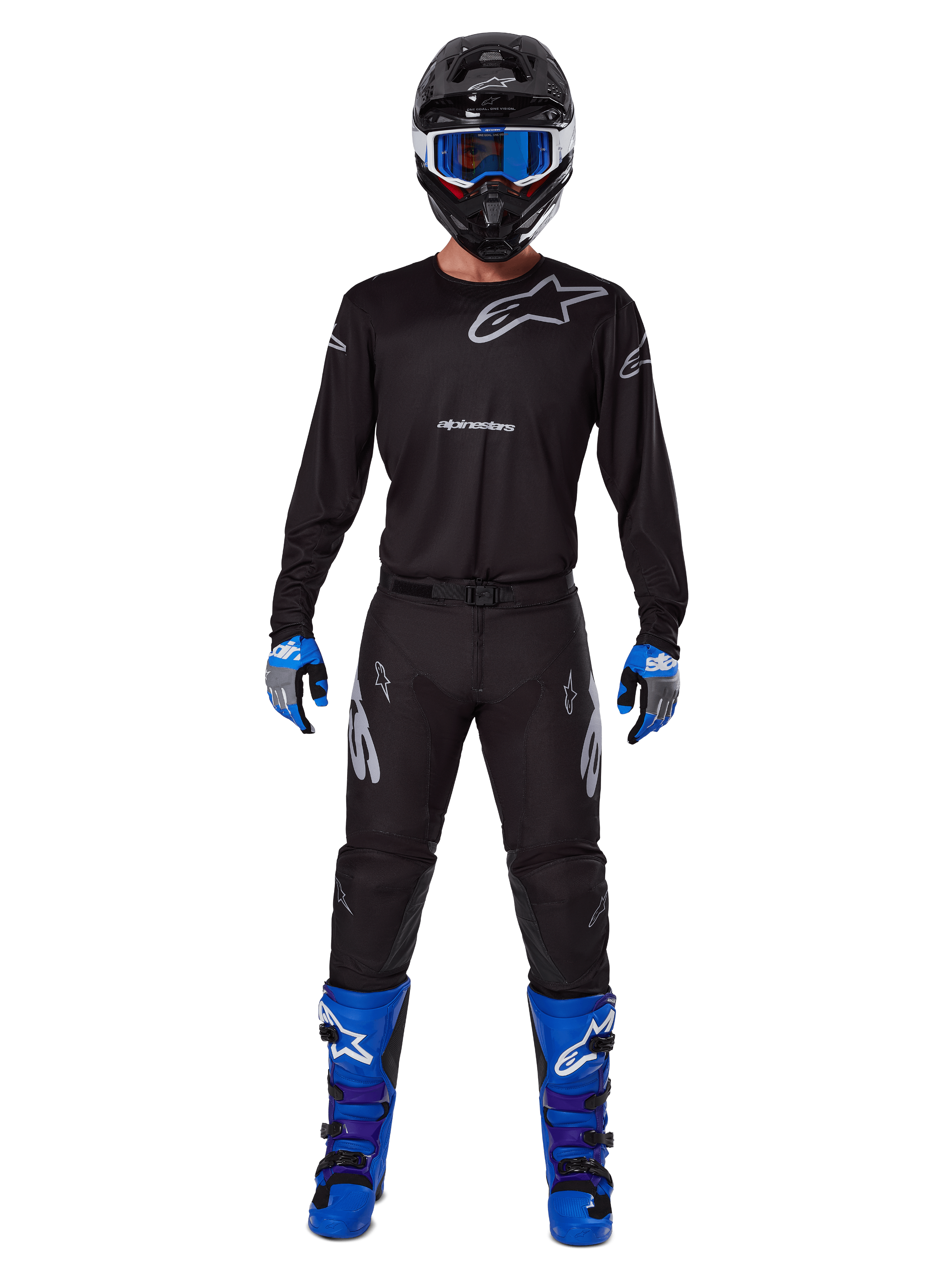 Alpinestars 2025 Racer Graphite Pants, pantaloni da motocross, nero e grigio, indossati da un modello con maglia nera abbinata, stivali blu e viola e occhiali blu, completo da corsa off-road con branding Alpinestars evidente