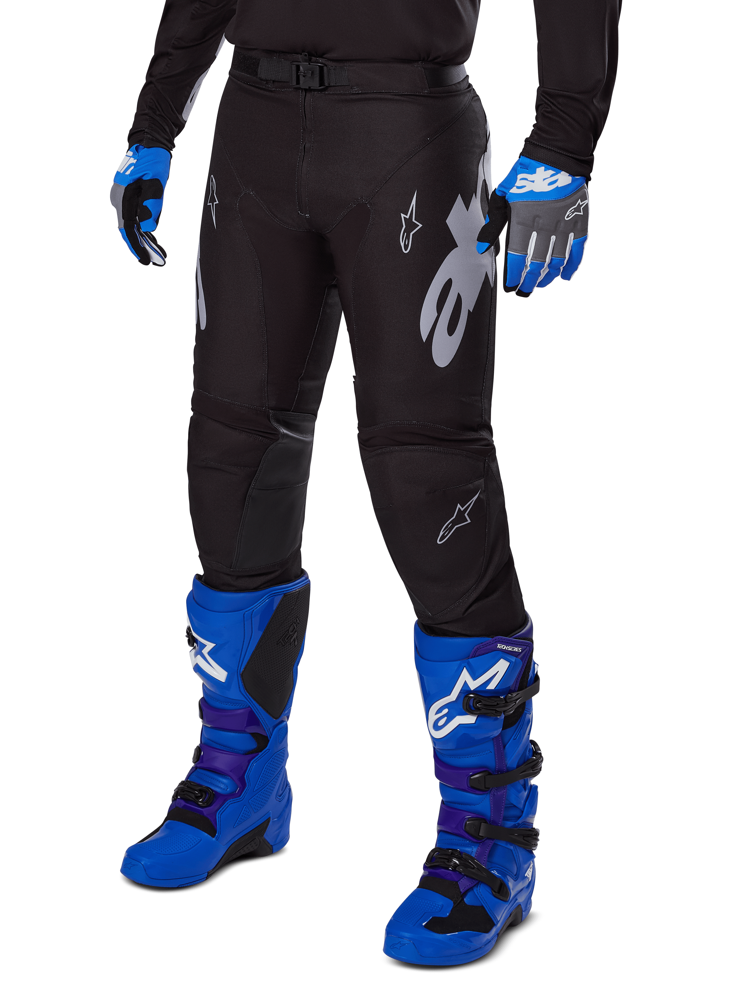 Alpinestars Pantaloni Racer Graphite 2025, pantaloni da motocross neri con grafiche bianche e grigie, indossati con stivali da motocross blu acceso e guanti blu coordinati, tessuto tecnico resistente per il fuoristrada