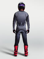 Alpinestars Pantaloni Racer Amber, pantaloni da motocross da uomo, grigio e lilla chiaro, vista posteriore con stivali rossi, abbigliamento tecnico off-road