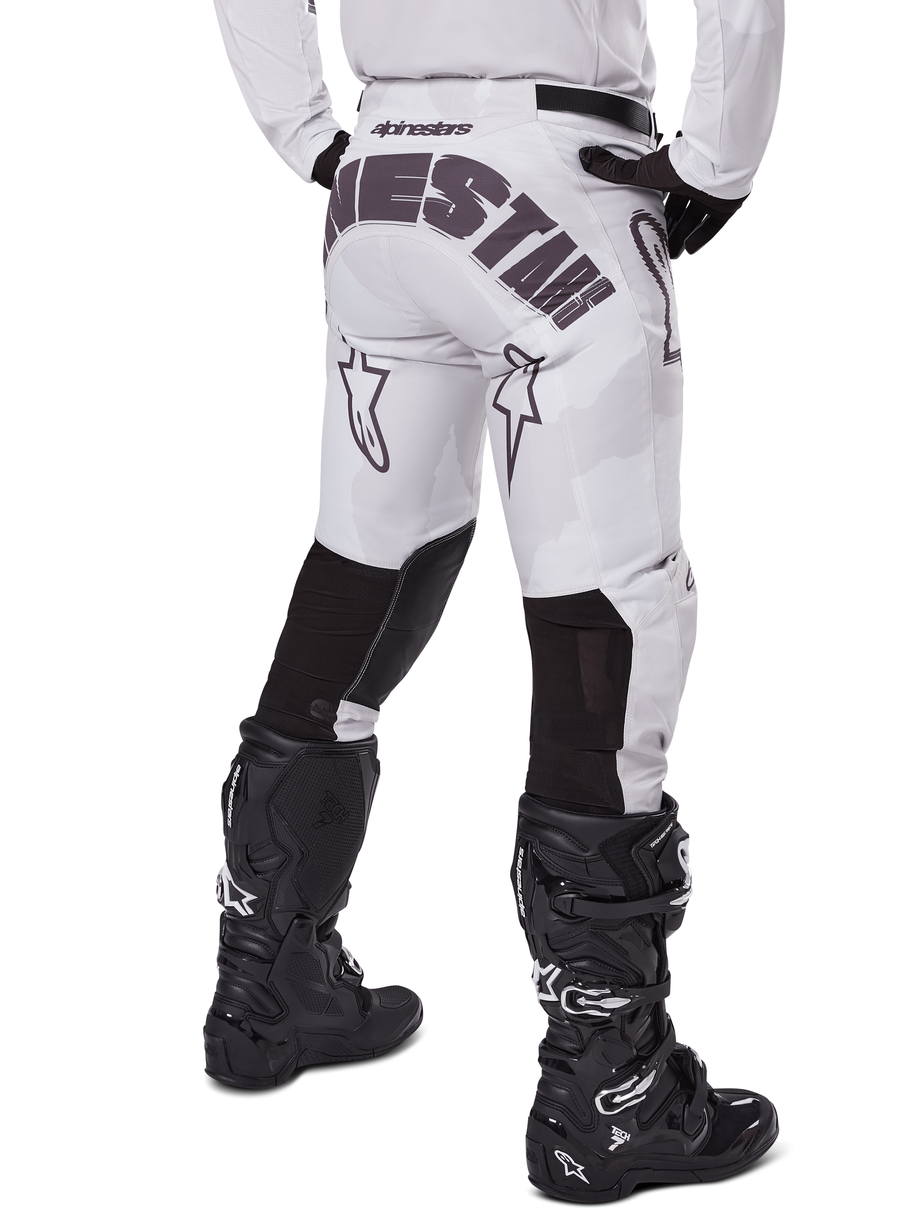 Alpinestars Racer Hollow 2025, pantaloni da motocross, Light Camo Brown, vista posteriore del pilota con grande marchio sulla seduta e pannelli elasticizzati neri sulla parte inferiore delle gambe, abbinati a stivali Tech 7 neri