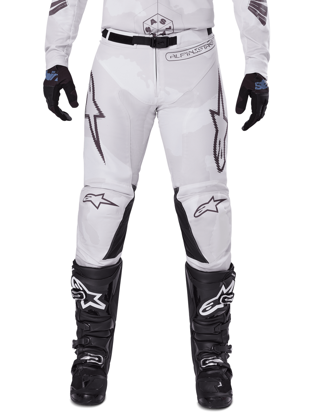 Alpinestars Pantaloni Racer Hollow 2025, pantaloni da motocross, Light Camo Brown, indossati con guanti neri e stivali da motocross, caratterizzati da un discreto motivo camouflage con grafiche nere e loghi Astars, design ergonomico per guida off-road