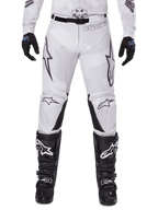 Alpinestars Pantaloni Racer Hollow 2025, pantaloni da motocross, Light Camo Brown, indossati con guanti neri e stivali da motocross, caratterizzati da un discreto motivo camouflage con grafiche nere e loghi Astars, design ergonomico per guida off-road