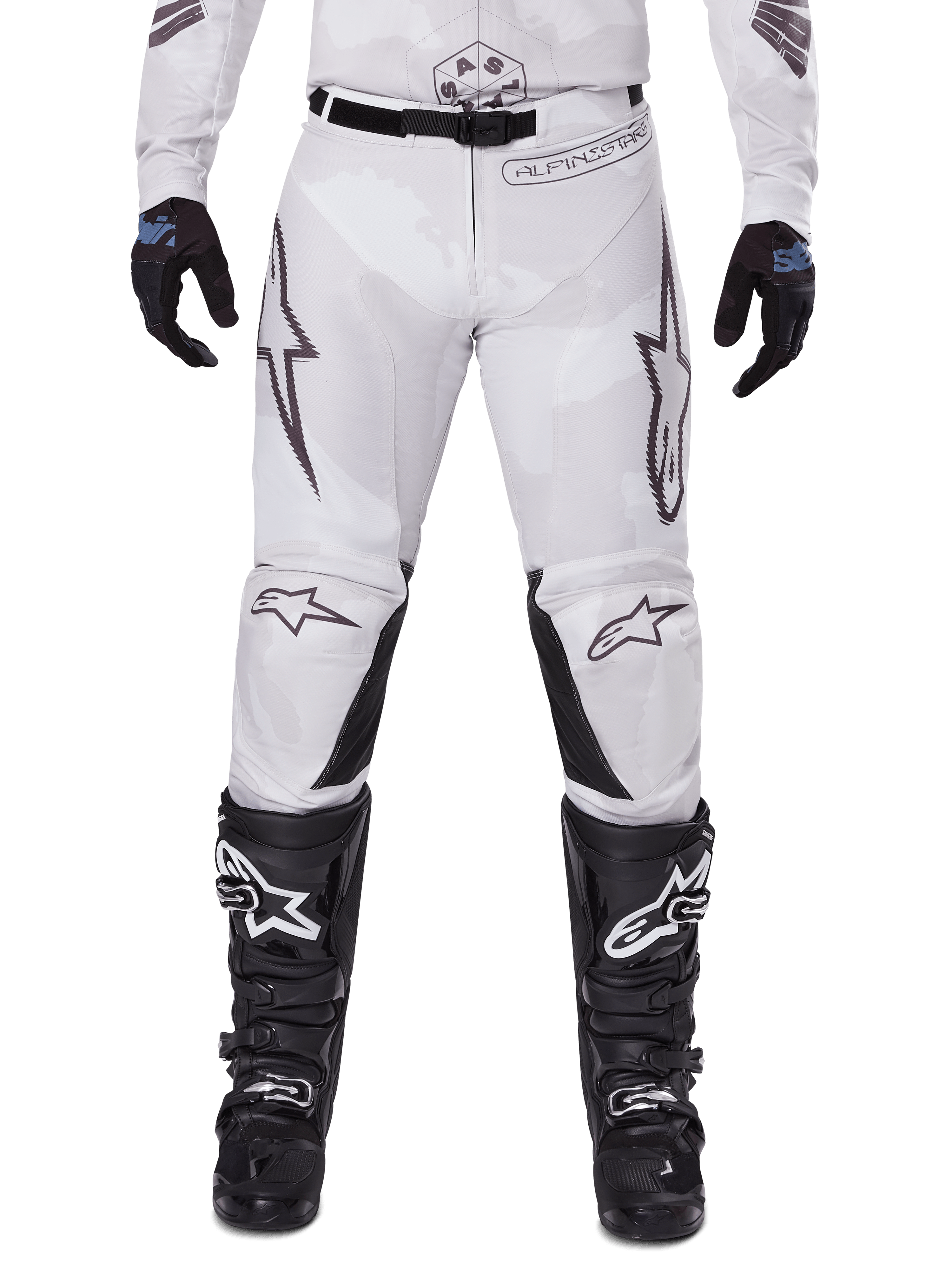 Alpinestars Pantaloni Racer Hollow 2025, pantaloni da motocross, Light Camo Brown, indossati con guanti neri e stivali da motocross, caratterizzati da un discreto motivo camouflage con grafiche nere e loghi Astars, design ergonomico per guida off-road