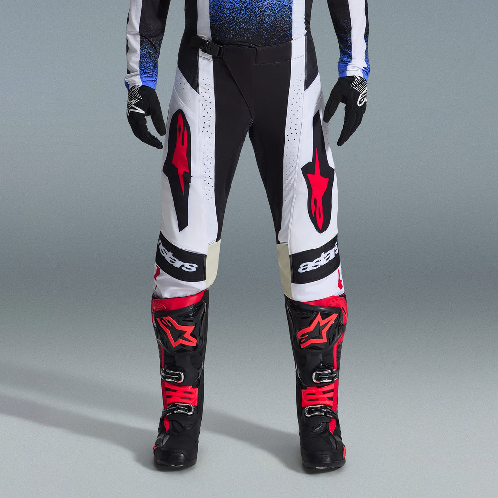 Set Completo Alpinestars Techstar Knif 2026, abbigliamento da motocross, pantaloni bianchi e neri con grandi loghi a stella rossi, indossato con stivali da gara neri e rossi e guanti neri, vestibilità atletica professionale per prestazioni off-road