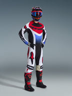 Alpinestars Techstar Knif Pants 2026, pantaloni da motocross, nero, bianco e rosso, indossati da un pilota con equipaggiamento da gara completo, maglia e stivali coordinati, con loghi Alpinestars rossi su pannelli bianchi e vestibilità atletica orientata alle prestazioni.