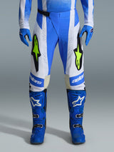 Alpinestars 2026 Techstar Knif Pants, pantaloni da motocross, blu UCLA, nero e giallo fluo, indossati con guanti e stivali blu coordinati, con pannelli bianchi e vivaci loghi giallo fluo, vestibilità racing ergonomica per prestazioni off-road