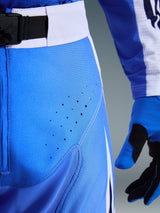 Alpinestars 2026 Techstar Knif Pants, blu Ucla e bianco, primo piano dell'area dell'anca con perforazioni tagliate al laser per la ventilazione, chiusura in vita con fibbia magnetica SX2 e guanti da motocross coordinati