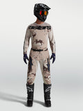 Alpinestars Racer Lone Gear Set, completo da motocross per uomo, maglia e pantaloni con grafica camouflage deserto sabbia, indossato con casco e stivali neri, abbigliamento tecnico per off-road.