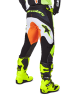 Alpinestars Pantaloni Fluid Wurx 2025, pantaloni da motocross, giallo e nero con dettagli arancioni e bianchi, vista posteriore indossati con stivali giallo brillante coordinati, design resistente per fuoristrada