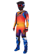 Pilota di motocross con abbigliamento da gara completo, pantaloni Alpinestars 2025 Fluid Wurx e maglia coordinata con sfumatura multicolore arancione, rossa e viola, casco nero con occhiali rossi, stivali blu e neri, guanti rossi e neri, outfit coordinato per corse fuoristrada
