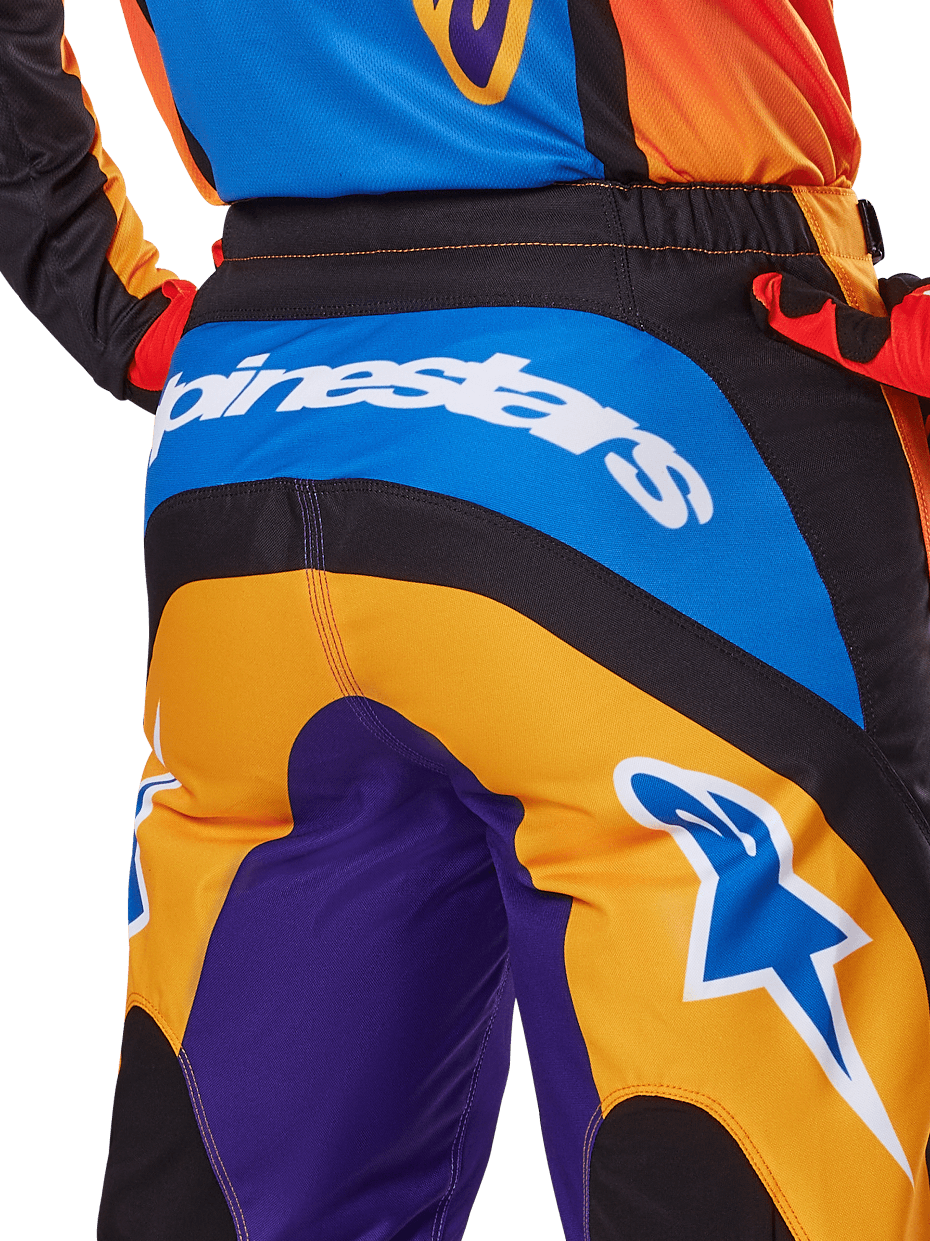 Alpinestars 2025 Fluid Wurx Pants, pantaloni da motocross, vista posteriore in arancione, blu e viola, con logo Alpinestars bianco sulla seduta e logo Astar blu sulla gamba, costruzione tecnica per il fuoristrada