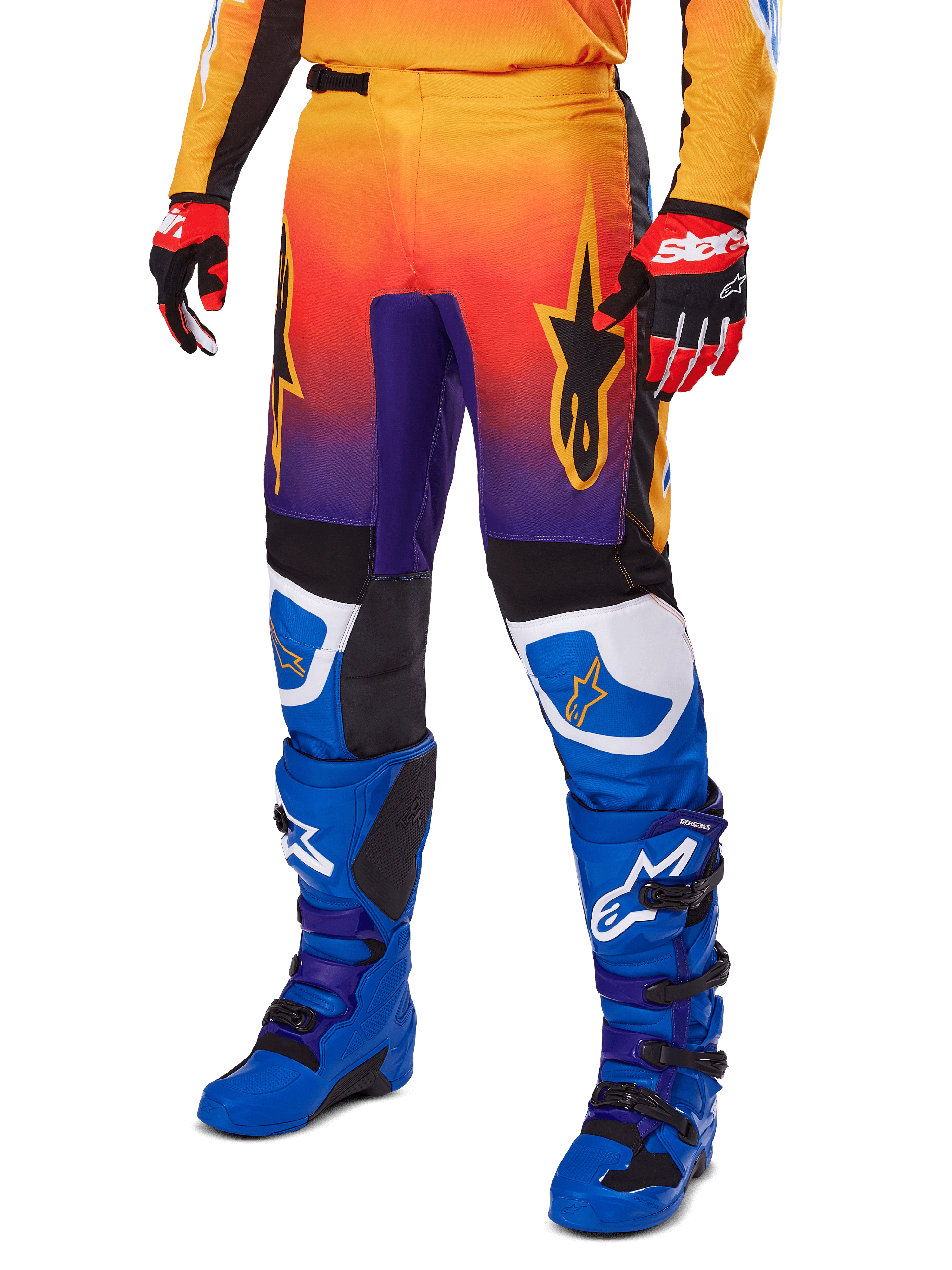 Alpinestars 2025 Fluid Wurx Pants, pantaloni da motocross, sfumatura multicolore arancione, rossa e viola con pannelli neri e blu, indossati con stivali blu e guanti rossi, con grafica del logo a stella e dettagli bianchi sulle ginocchia, abbigliamento tecnico resistente per fuoristrada