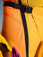 Alpinestars 2026 Techstar Nomur Pants, pantaloni da motocross, arancio giallo rosa, primo piano della zona vita con chiusura magnetica SX2, cinturino di regolazione nero e fori di ventilazione laser su tessuto ripstop resistente
