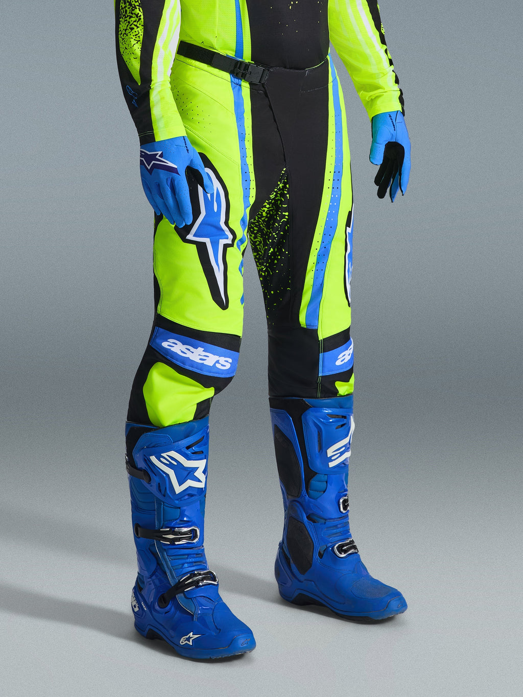Alpinestars pantaloni Techstar Nomur 2026, pantaloni da motocross, giallo fluo, blu navy scuro e blu UCLA, indossati con stivali e guanti blu abbinati, con vistosi loghi bianchi e pannelli rinforzati, abbigliamento professionale per competizioni off-road