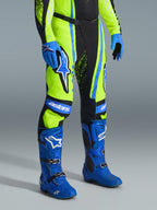 Alpinestars pantaloni Techstar Nomur 2026, pantaloni da motocross, giallo fluo, blu navy scuro e blu UCLA, indossati con stivali e guanti blu abbinati, con vistosi loghi bianchi e pannelli rinforzati, abbigliamento professionale per competizioni off-road