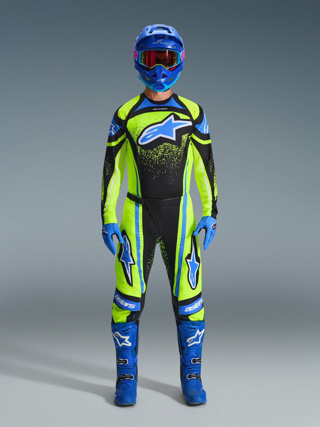 Pilota di motocross con abbigliamento completo da gara, pantaloni e maglia Alpinestars Techstar Nomur 2026 in giallo fluo e blu scuro, con accenti e loghi blu, abbinati a casco, guanti e stivali blu per un look da gara off-road coordinato.