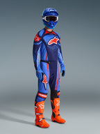 Alpinestars Pantaloni Techstar Nomur 2026, pantaloni da motocross, Dark Navy Orange e UCLA Blue, indossati da un pilota con abbigliamento da gara completo comprensivo di maglia coordinata, casco blu e stivali arancione acceso, progettati per prestazioni elevate nel motocross off-road