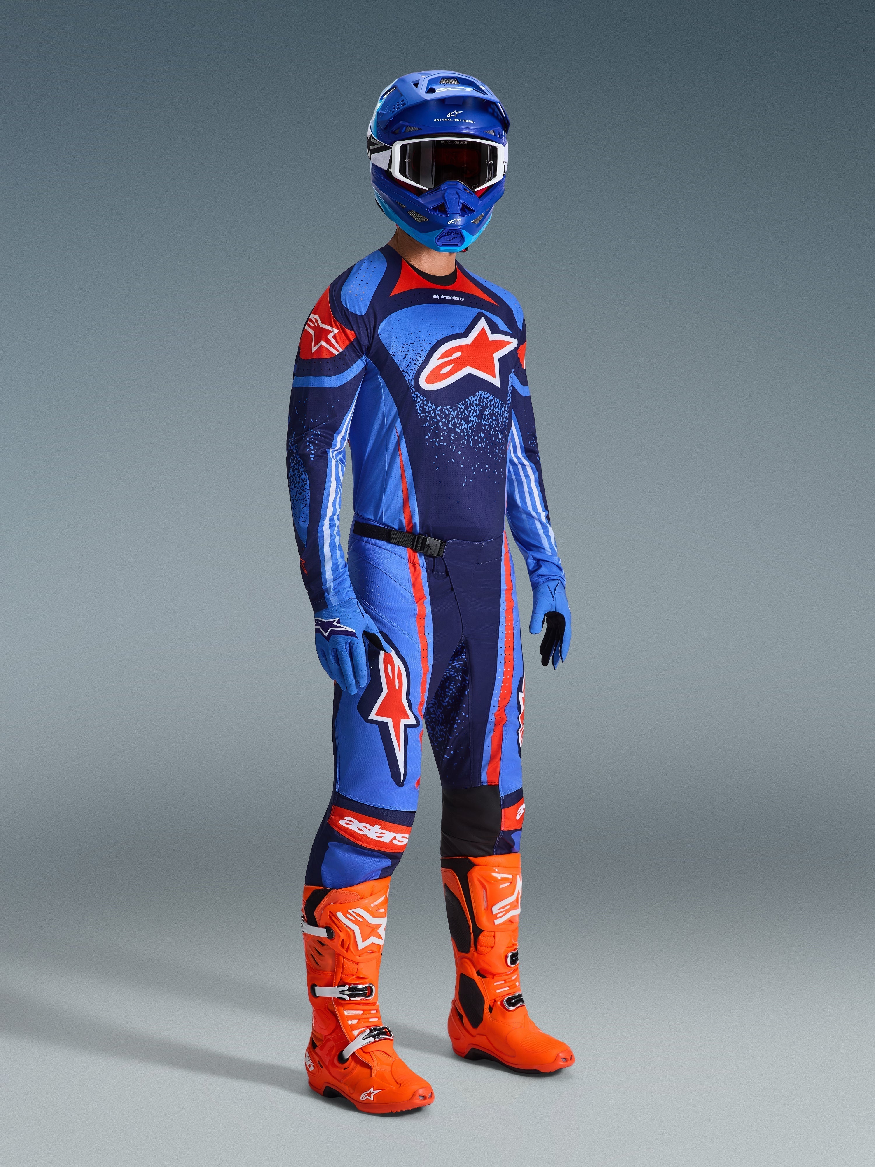 Alpinestars Pantaloni Techstar Nomur 2026, pantaloni da motocross, Dark Navy Orange e UCLA Blue, indossati da un pilota con abbigliamento da gara completo comprensivo di maglia coordinata, casco blu e stivali arancione acceso, progettati per prestazioni elevate nel motocross off-road