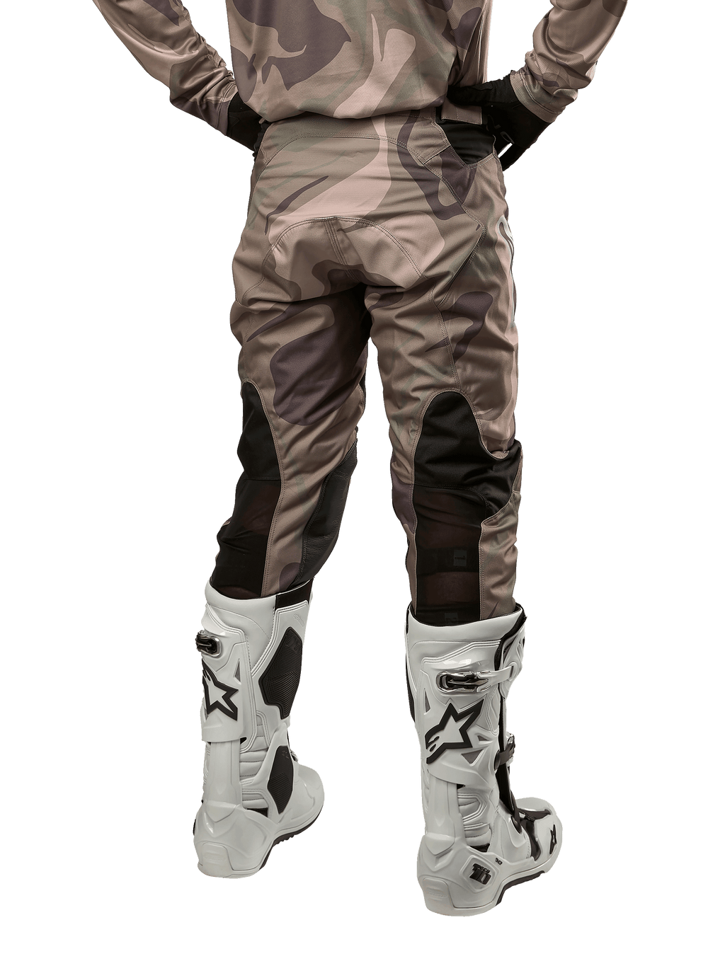 Alpinestars 2024 Racer Tactical Pants, pantaloni da motocross, mimetico verde militare e marrone, vista posteriore che mostra il motivo mimetico e i pannelli elastici neri traspiranti sulla parte inferiore delle gambe, indossati con stivali bianchi da motocross, attrezzatura tecnica resistente per la guida fuoristrada