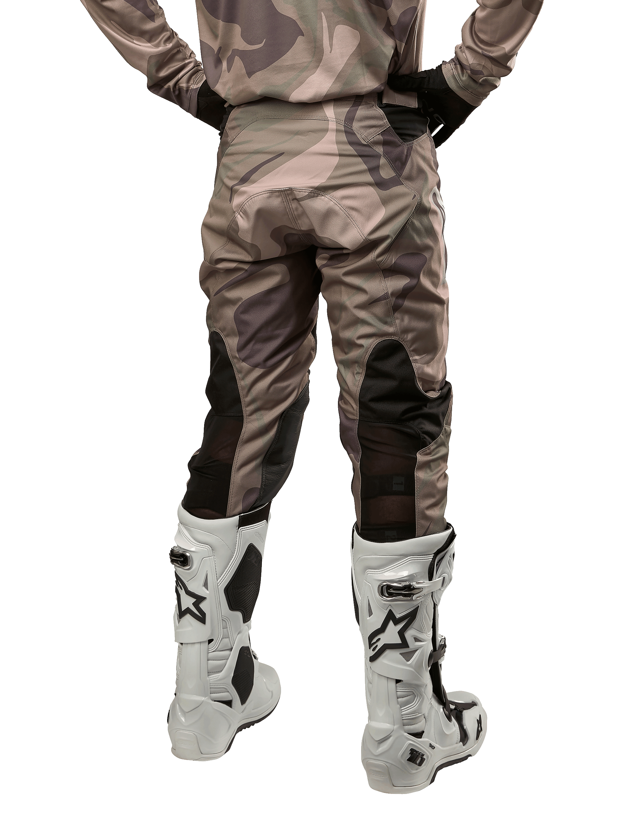 Alpinestars 2024 Racer Tactical Pants, pantaloni da motocross, mimetico verde militare e marrone, vista posteriore che mostra il motivo mimetico e i pannelli elastici neri traspiranti sulla parte inferiore delle gambe, indossati con stivali bianchi da motocross, attrezzatura tecnica resistente per la guida fuoristrada