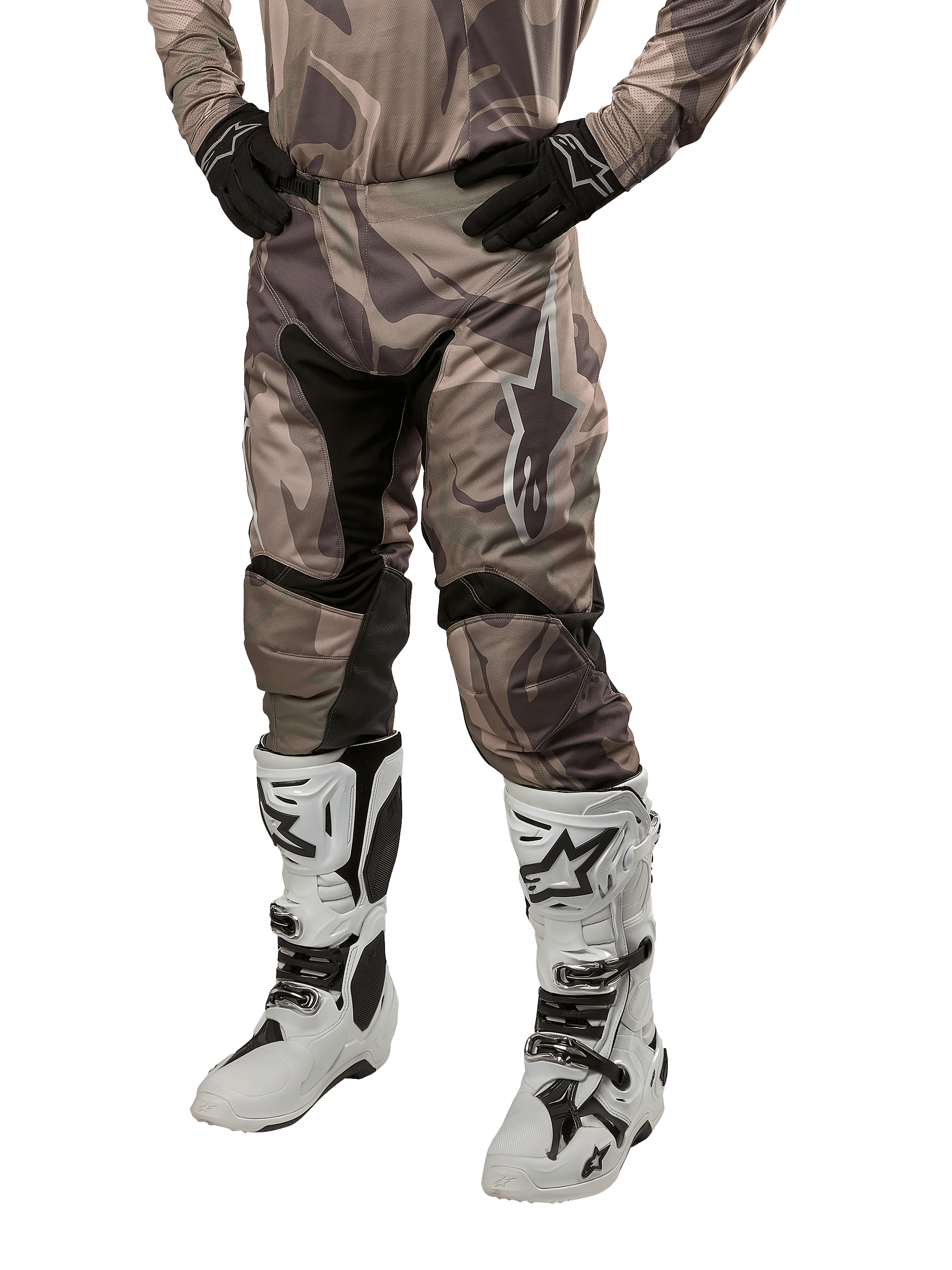 Alpinestars 2024 Racer Tactical Pants, pantaloni da motocross, mimetico verde militare e marrone, indossati con maglia mimetica coordinata, guanti neri e stivali bianchi con loghi a stella, con pannelli elastici neri e design ergonomico, kit da fuoristrada su sfondo bianco