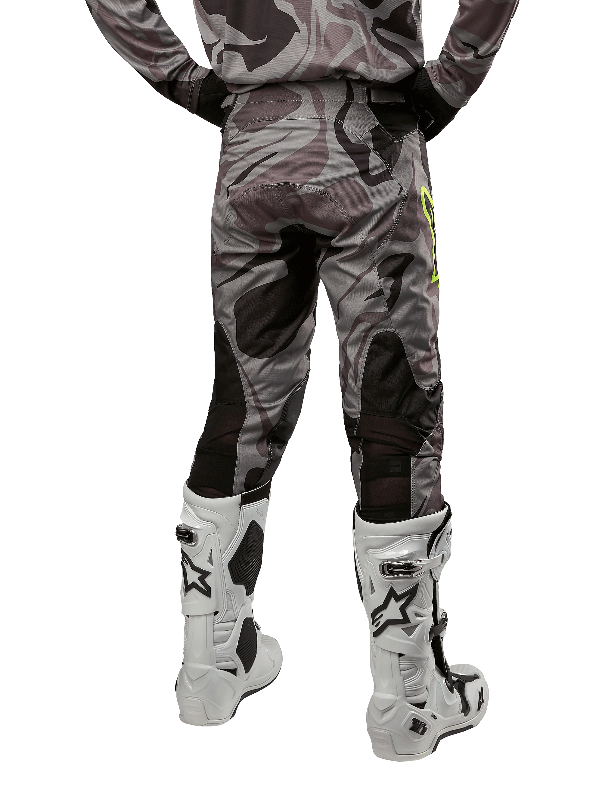 Alpinestars 2024 Racer Tactical Pants, pantaloni da motocross, Cast Gray Camo Magnet, vista posteriore con motivo mimetico e zone elasticizzate traspiranti nere, indossati con stivali da motocross bianchi e neri, progettati per il racing fuoristrada.