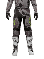 Alpinestars Pantaloni Racer Tactical 2024, pantaloni da motocross, Cast Gray Camo Magnet, indossati con maglia camo coordinata, guanti neri e stivali bianchi e neri, con loghi a stella verde lime sulle cosce e pannelli elasticizzati neri, vista frontale per equipaggiamento da fuoristrada