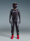 Set completo Alpinestars 2026 Fluid Apex, outfit da motocross, nero con accenti grigi, maglia con grande logo Astars bianco, pantaloni coordinati con marchio vistoso, casco nero con occhiali rosa e stivali rosso brillante, kit completo per corse off-road