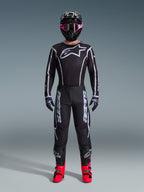 Set completo Alpinestars 2026 Fluid Apex, outfit da motocross, nero con accenti grigi, maglia con grande logo Astars bianco, pantaloni coordinati con marchio vistoso, casco nero con occhiali rosa e stivali rosso brillante, kit completo per corse off-road