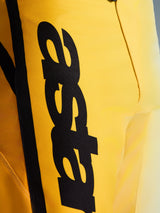 Primo piano dei pantaloni Alpinestars 2026 Fluid Apex, pantaloni da motocross, giallo e nero, con un grande logo nero verticale, materiale resistente e testurizzato e dettagli ergonomici per prestazioni off-road