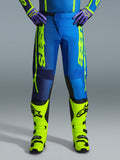 Alpinestars 2026 Fluid Apex Pants, pantaloni da motocross, blu e giallo fluo, indossati con stivali giallo fluo coordinati e guanti viola, branding giallo vivace sui lati, design ergonomico per corse fuoristrada