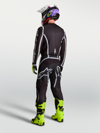 Alpinestars pantaloni Fluid Apex V2, pantaloni da motocross da uomo, nero e argento, vista posteriore con maglia coordinata e stivali giallo neon, abbigliamento tecnico per fuoristrada