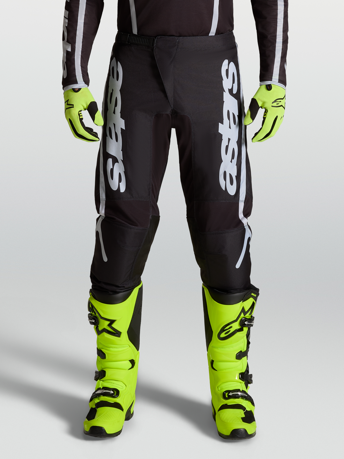 Alpinestars pantaloni da motocross Fluid Apex V2 2027 da uomo neri e argento, con pannelli stretch ergonomici su modello.