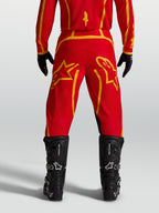 Alpinestars Pantaloni Fluid Apex V2, pantaloni motocross da uomo, rossi e oro, vista posteriore con stivali neri