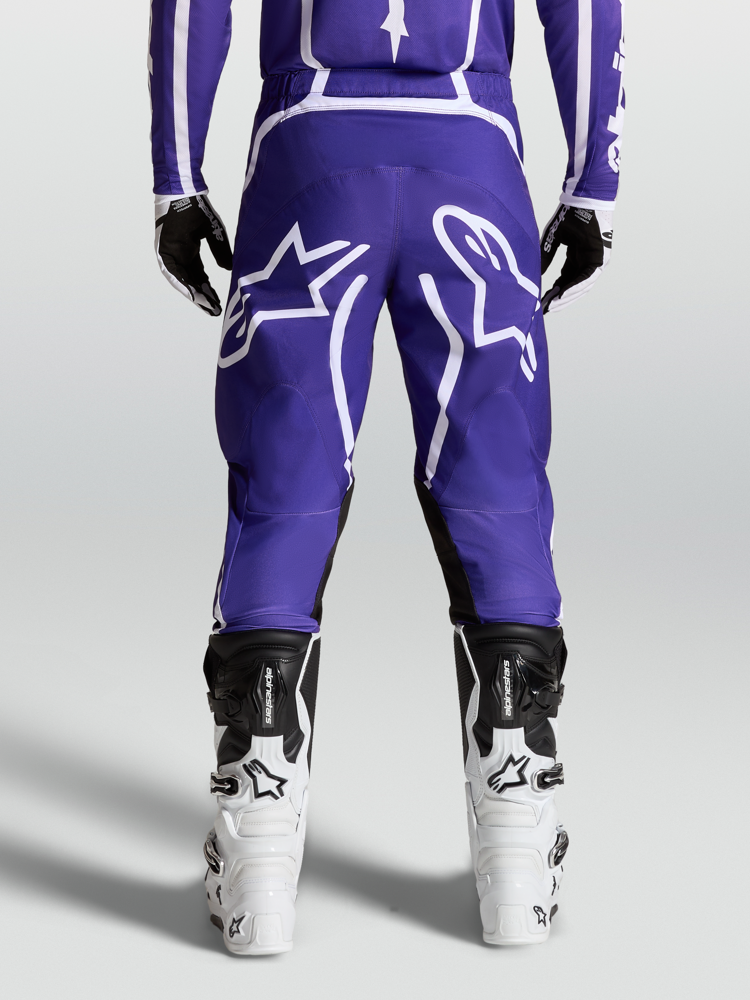 Alpinestars Pantaloni Fluid Apex V2, pantaloni motocross da uomo, blu scuro e bianchi, vista posteriore con stivali, in poliestere 600D resistente