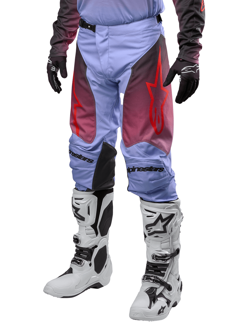 Alpinestars Racer Hoen Pants 2024, pantaloni da motocross, viola Lavan e nero con grafiche rosse, con loghi a stella rossi sulle cosce e scritte nere sulle ginocchia, indossati con stivali bianchi e neri e guanti neri