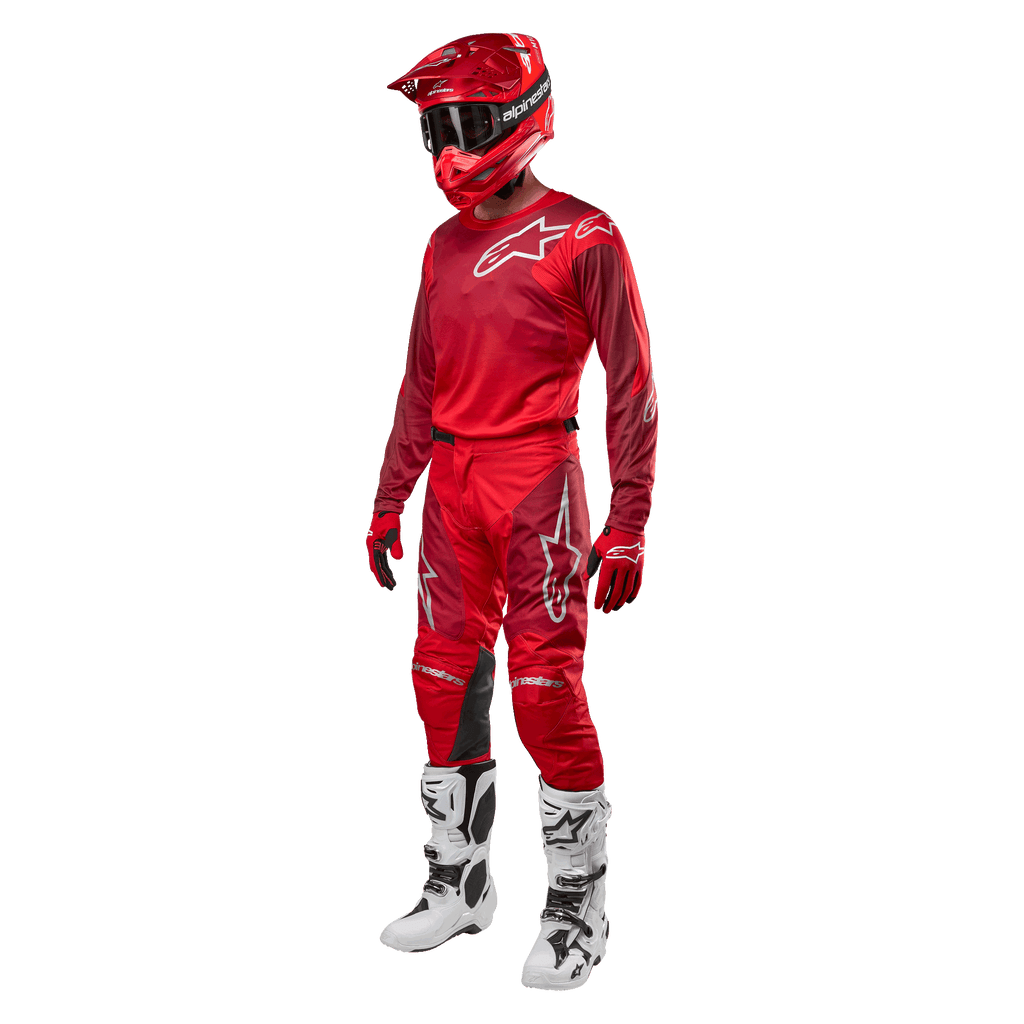 Pilota di motocross con equipaggiamento completo da gara, pantaloni e maglia Alpinestars Racer Hoen 2024 in Mars Red Burgundy, casco rosso, guanti rossi e stivali bianchi e neri, completo coordinato per il fuoristrada