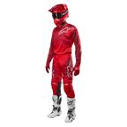 Pilota di motocross con equipaggiamento completo da gara, pantaloni e maglia Alpinestars Racer Hoen 2024 in Mars Red Burgundy, casco rosso, guanti rossi e stivali bianchi e neri, completo coordinato per il fuoristrada