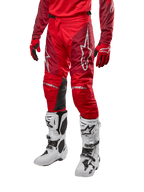 Alpinestars pantaloni Racer Hoen 2024, pantaloni da motocross, rosso Marte e bordeaux, indossati con maglia e guanti rossi coordinati e stivali bianchi, con inserti in pelle nera sulle ginocchia e loghi bianchi, abbigliamento tecnico resistente per fuoristrada