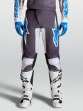 Alpinestars pantaloni Fluid Drag, pantaloni da motocross grigi e blu, design ergonomico con gambe precurvate, indossati da un pilota con stivali bianchi
