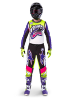 Pilota di motocross con abbigliamento completo da gara, maglia e pantaloni Limited Edition Supertech Dirt Studios in bianco, viola e giallo fluo, casco nero con occhiali, stivali viola e bianchi, completo coordinato dai colori vivaci per motocross fuoristrada